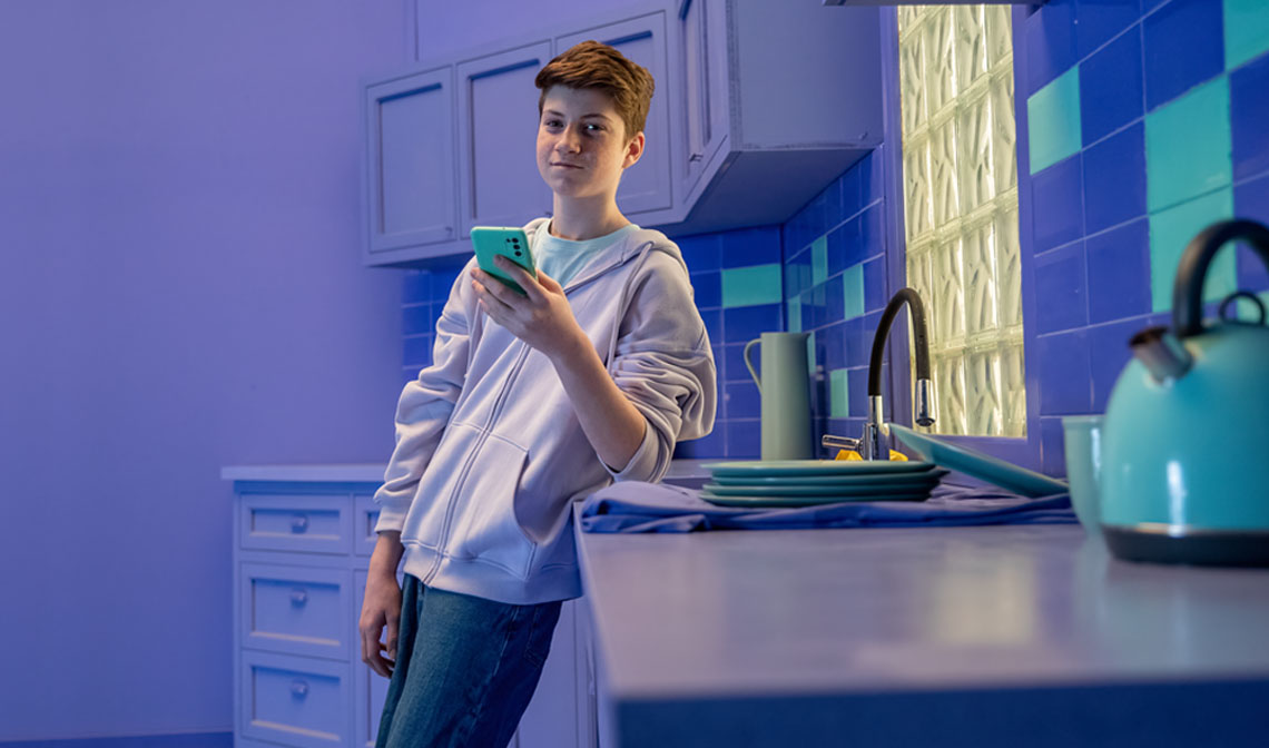 Boy leaning at a sink phone in hand