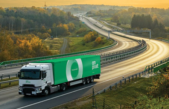 An Post lorry driving on a motorway at sunset