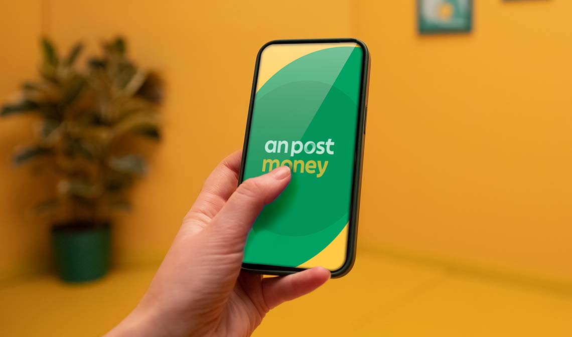 Hand holding phone showing the An Post Money app