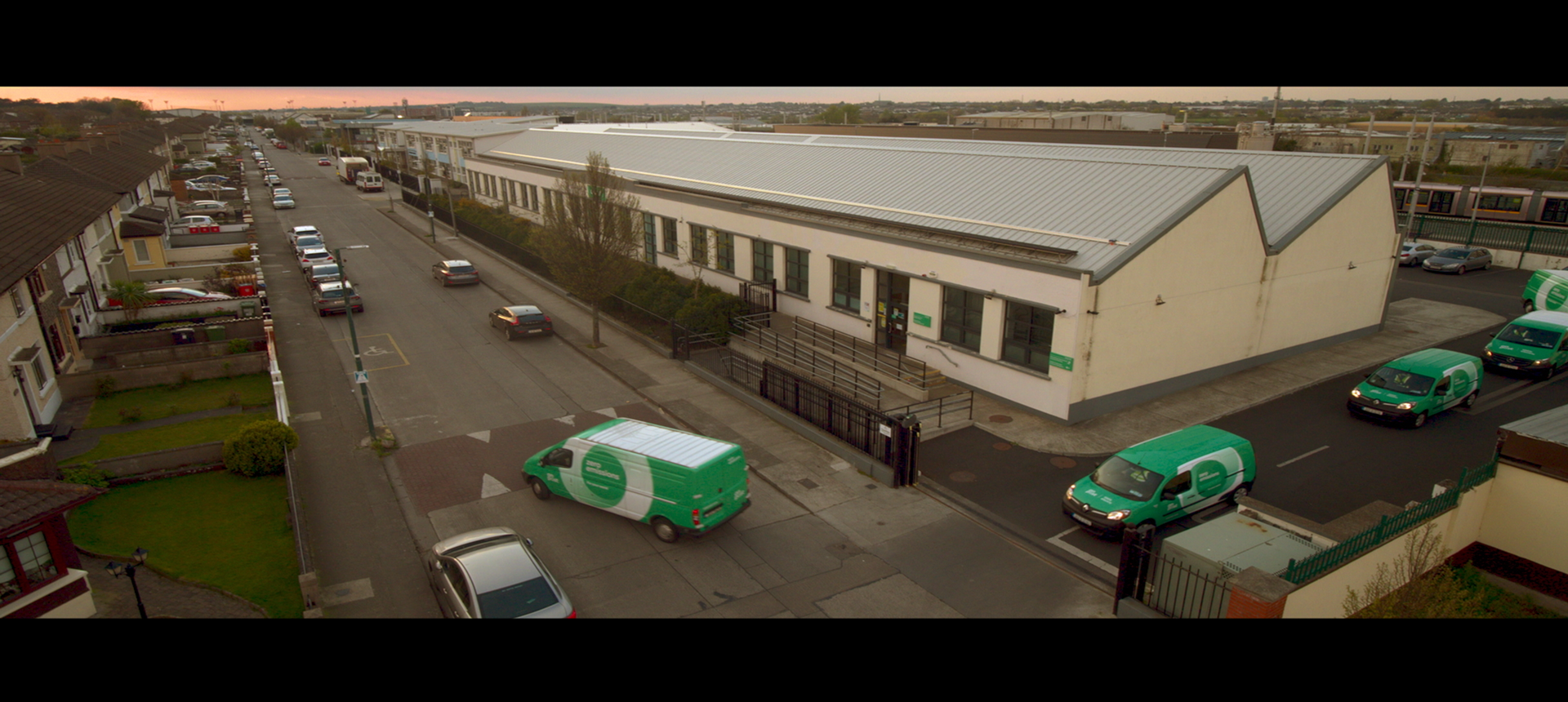 Photograph looking down on an An Post building with a line of An Post zero emission vehicles driving out.