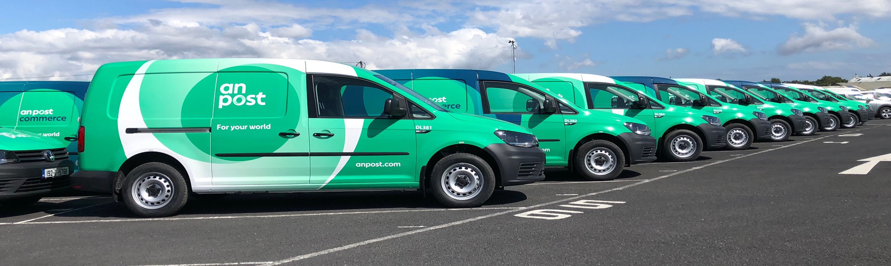 Line up of parked An Post zero emission vehicles.