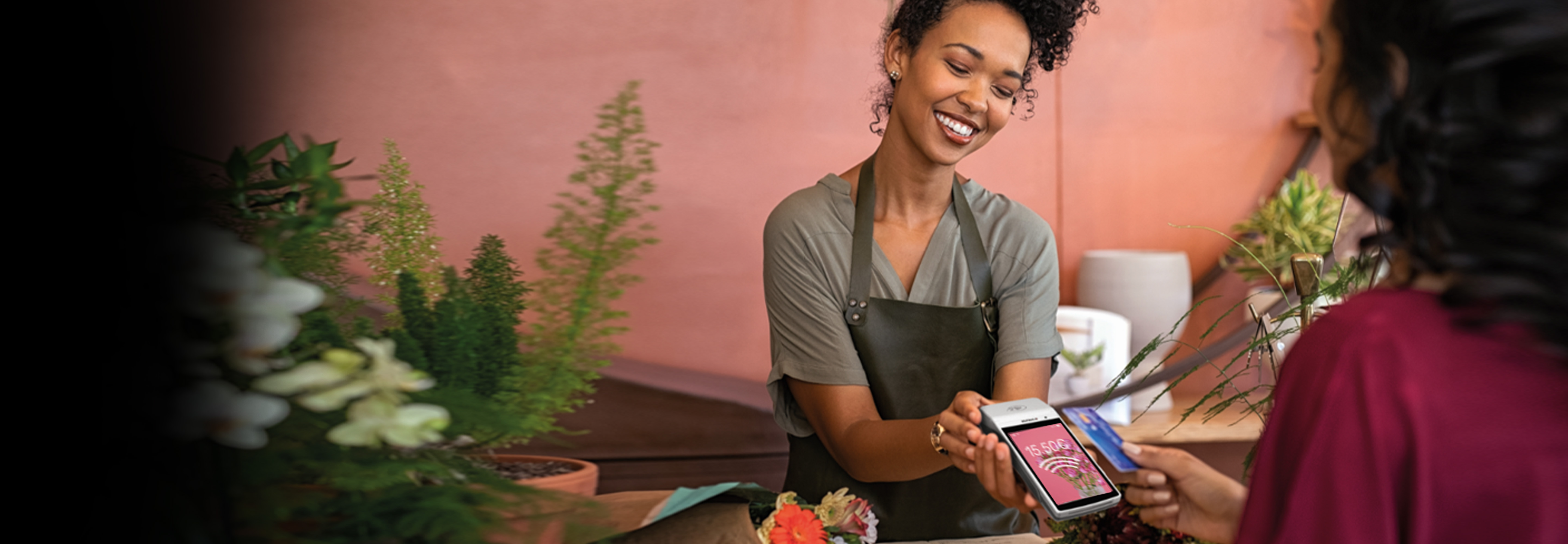 A salesperson in an apron taking card payment from a customer 