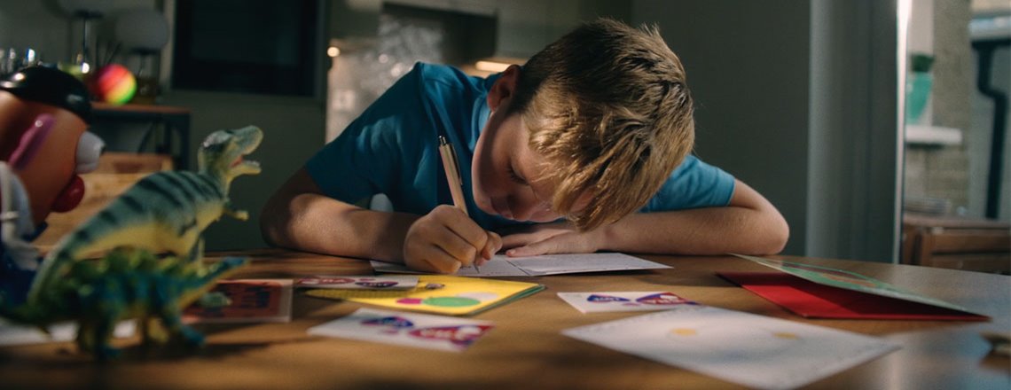 Child writes a birthday card at his kitchen table