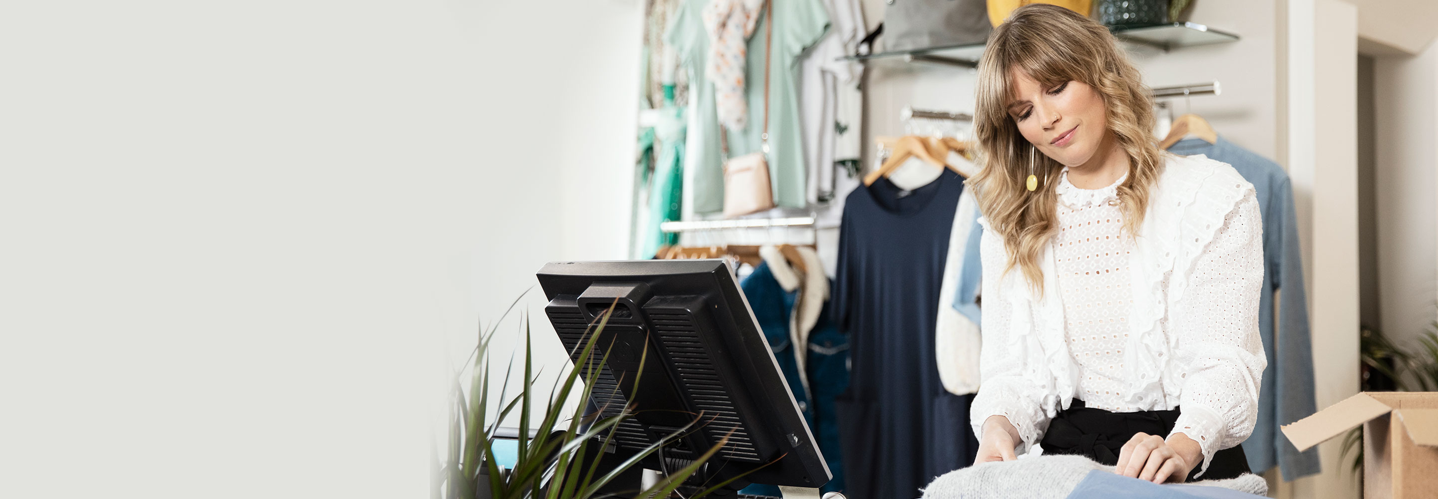 woman in her boutique packaging up her ecommerce orders to deliver to customers