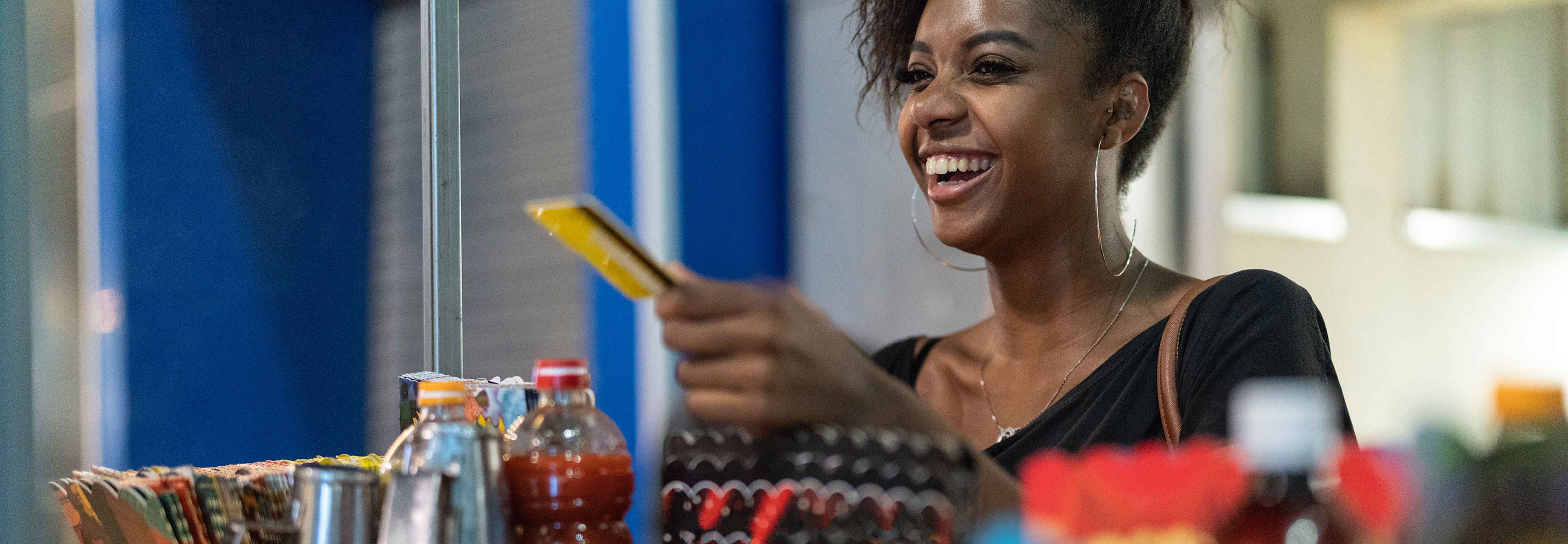 A woman smiling while paying with her debit card