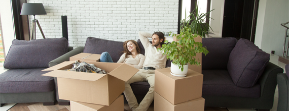 Man and woman sitting on couch surrounded with boxes