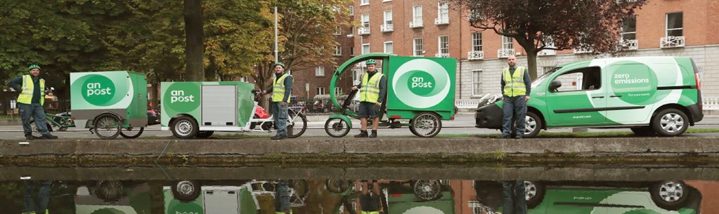 Variety of An Post zero emission vehicles and staff along the canal.