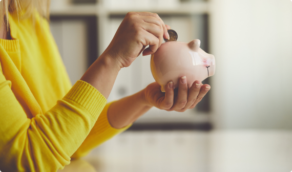 Woman in yellow sweatshirt putting coin in pink piggy bag