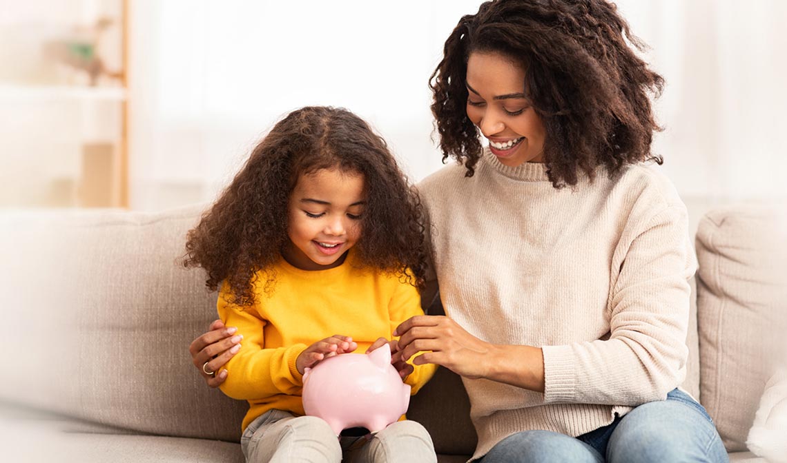 Mother and daughter holding a pink piggy bank