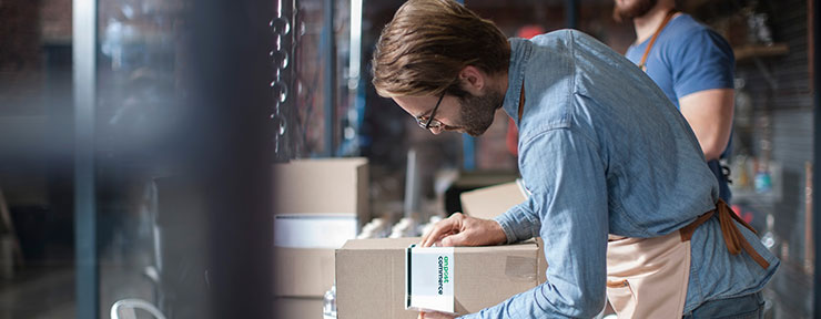 A man in a blue shirt labelling a box package