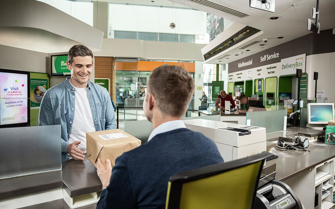 ecommerce website owner at the counter of his local post office posting a package to a customer