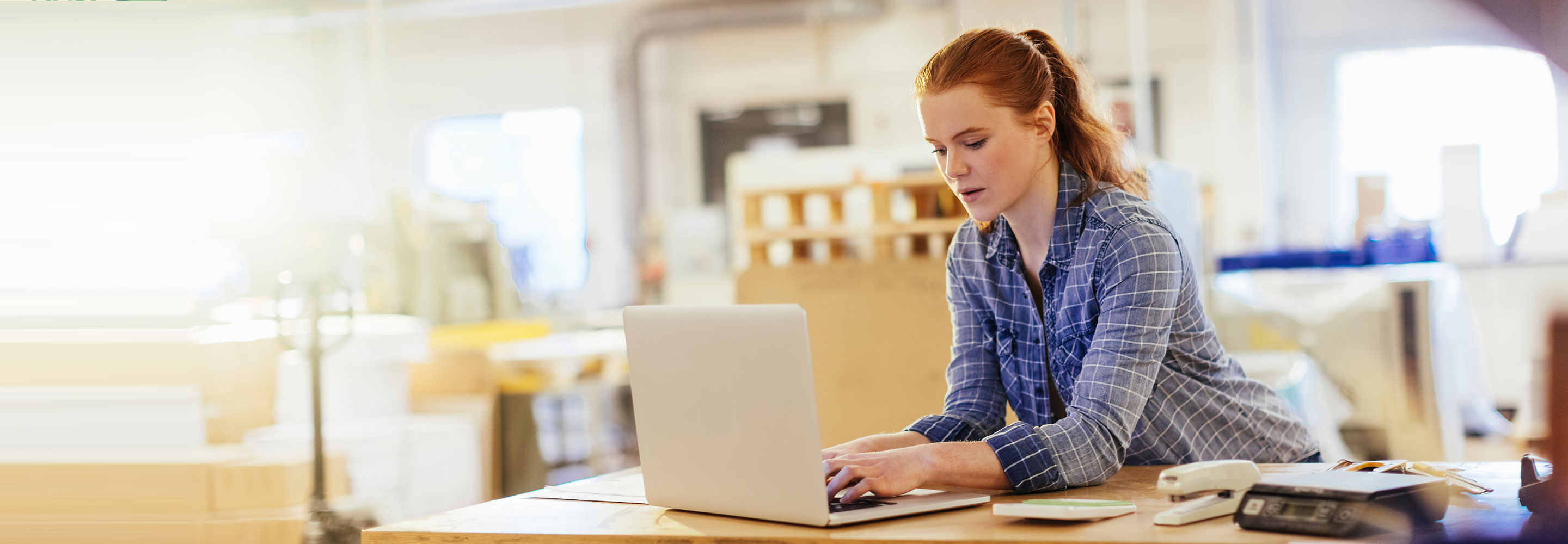 woman in an open plan office searching for information on her laptop