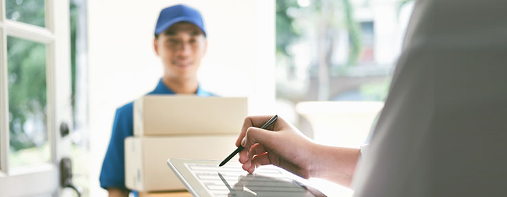 A person accepting a delivery of brown boxes