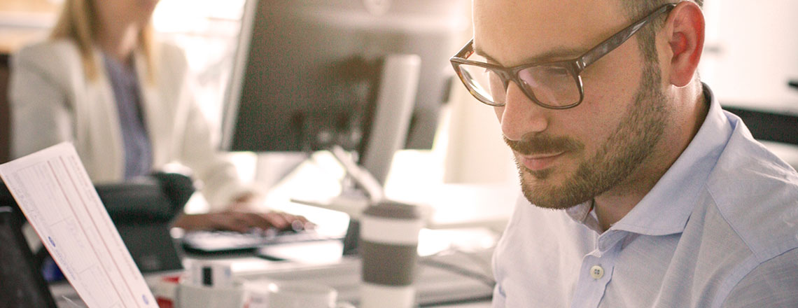 man in a busy office analysing data from a printed business.ie report 