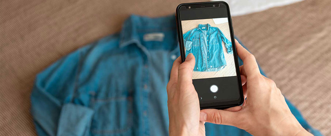 Person taking a picture of a denim shirt for reselling